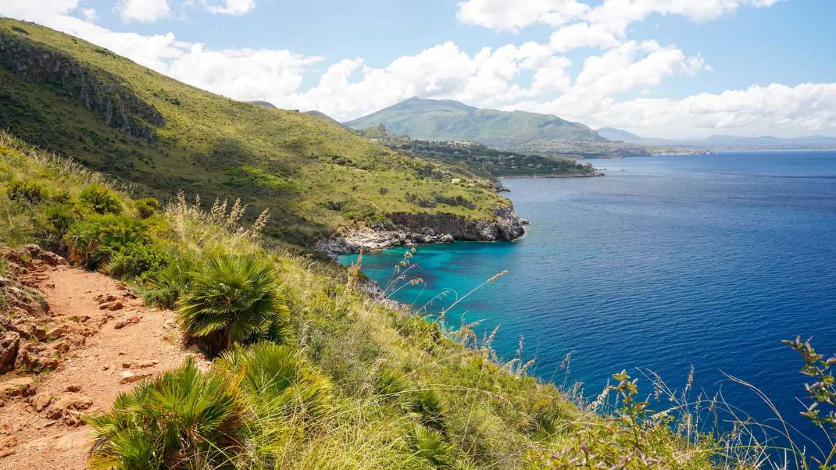 Panorama mozzafiato di un trekking in Sardegna, con montagne e mare cristallino sullo sfondo.