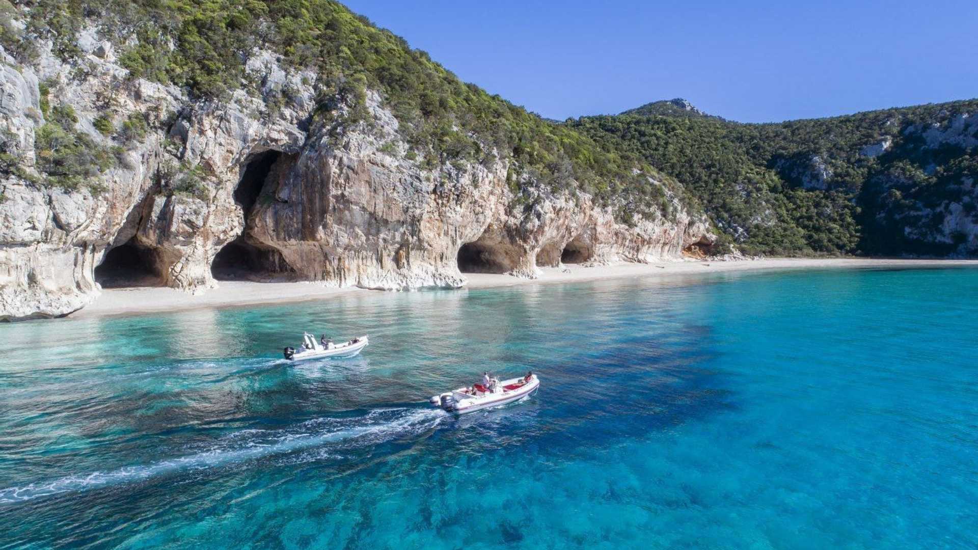 Caletta sarda con acque turchesi e sabbia bianca, immersa nella natura incontaminata.