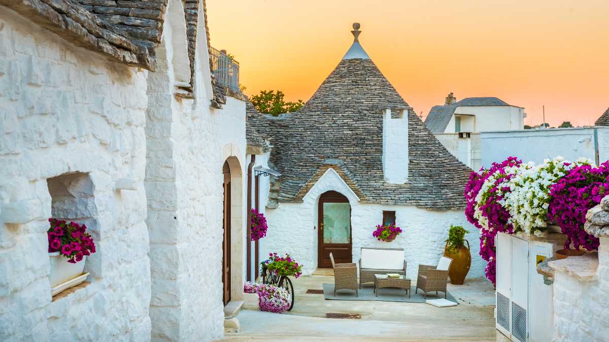 Trullo tradizionale in Puglia circondato da ulivi, simbolo degli alloggi tipici italiani.